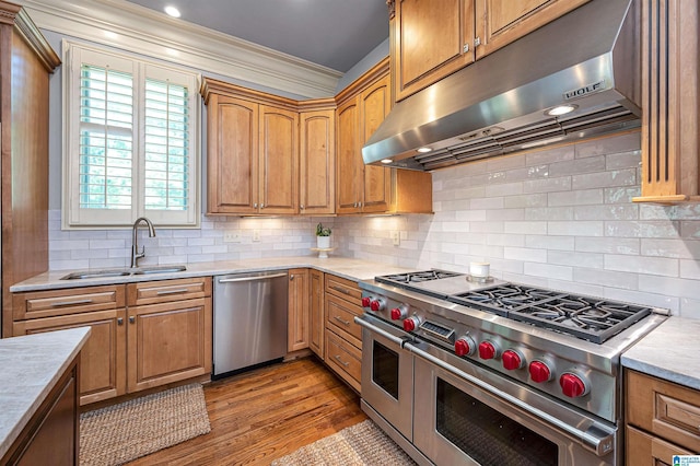 kitchen featuring a sink, under cabinet range hood, light countertops, ornamental molding, and appliances with stainless steel finishes