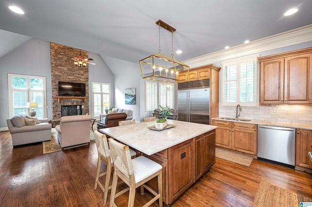 kitchen with a sink, dark wood-style flooring, a kitchen island, appliances with stainless steel finishes, and open floor plan