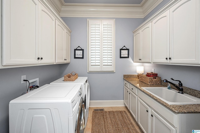 clothes washing area featuring washing machine and clothes dryer, crown molding, a sink, baseboards, and cabinet space