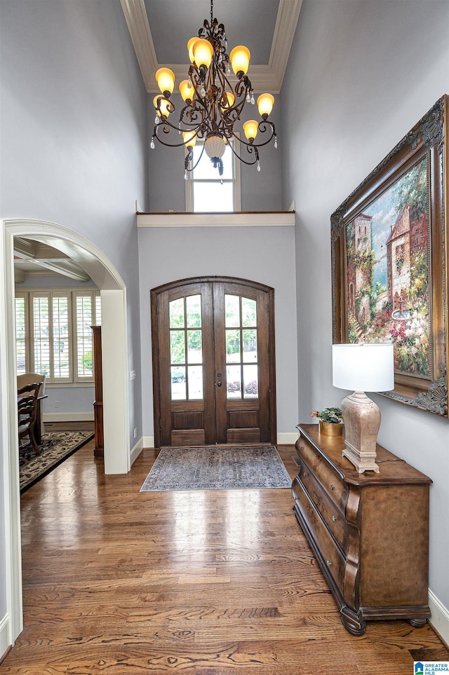 foyer featuring ornamental molding, a chandelier, wood finished floors, and french doors