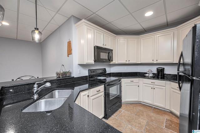 kitchen with dark stone counters, a paneled ceiling, a sink, stone tile floors, and black appliances