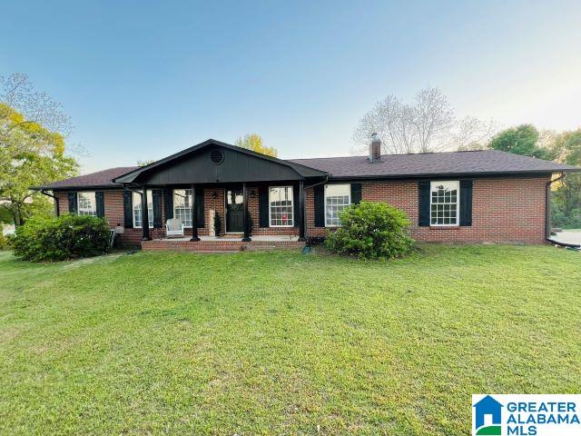 ranch-style home featuring a front lawn, brick siding, and a porch