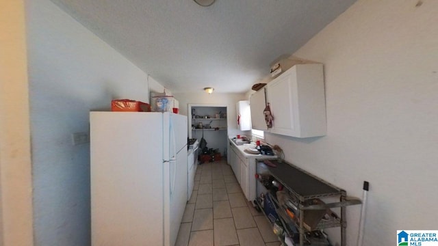kitchen featuring freestanding refrigerator, white cabinetry, and light tile patterned floors