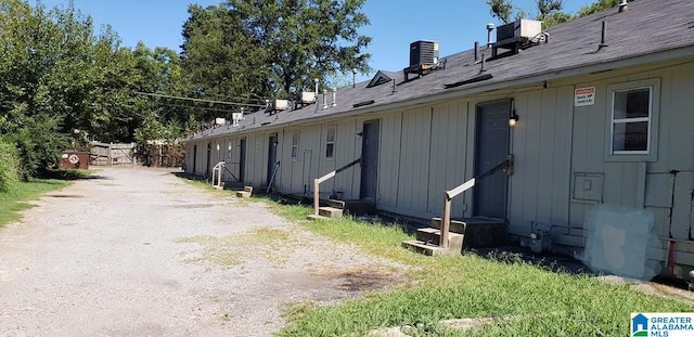 view of side of property with board and batten siding, entry steps, and cooling unit
