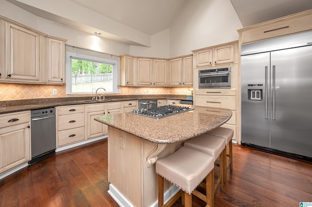 kitchen featuring tasteful backsplash, a sink, stainless steel appliances, a center island, and dark wood-style flooring