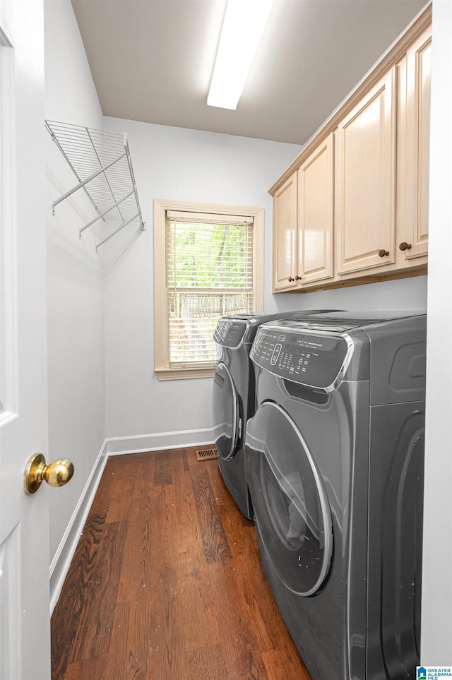 washroom with visible vents, dark wood-style floors, baseboards, washer and dryer, and cabinet space