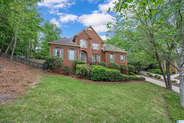 view of front of property featuring brick siding, fence, a shingled roof, and a front yard