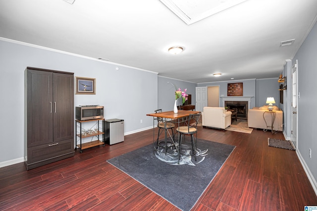 dining area featuring baseboards, visible vents, dark wood-style flooring, and a fireplace