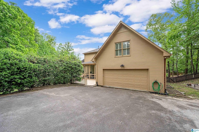 view of property exterior with a garage, fence, and driveway