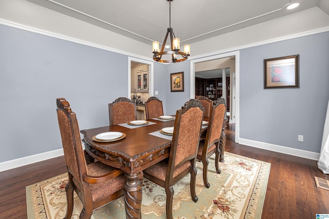 dining area featuring a chandelier, baseboards, wood finished floors, and visible vents