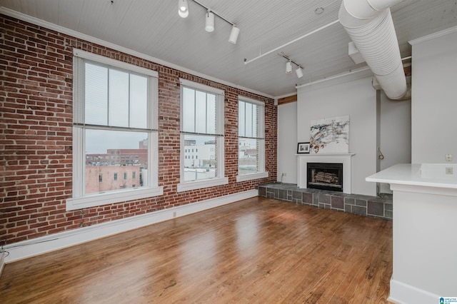 113 N 22nd St Unit 403, Birmingham, AL 35203 - unfurnished living room with wood finished floors, brick wall, a fireplace, and track lighting