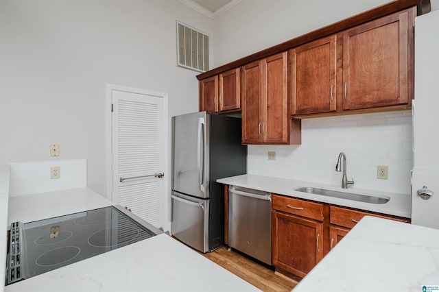113 N 22nd St Unit 403, Birmingham, AL 35203 - kitchen featuring stainless steel appliances, ornamental molding, tasteful backsplash, brown cabinets, and light wood-type flooring