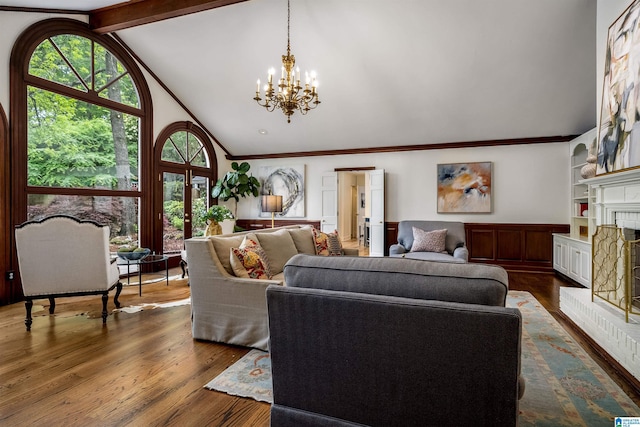 living area featuring a brick fireplace, ornamental molding, wood finished floors, and a chandelier