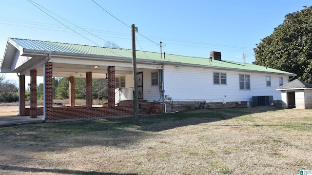 exterior space featuring a chimney, cooling unit, metal roof, and a front yard