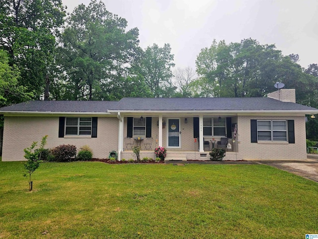 single story home featuring a chimney, brick siding, a front yard, and covered porch