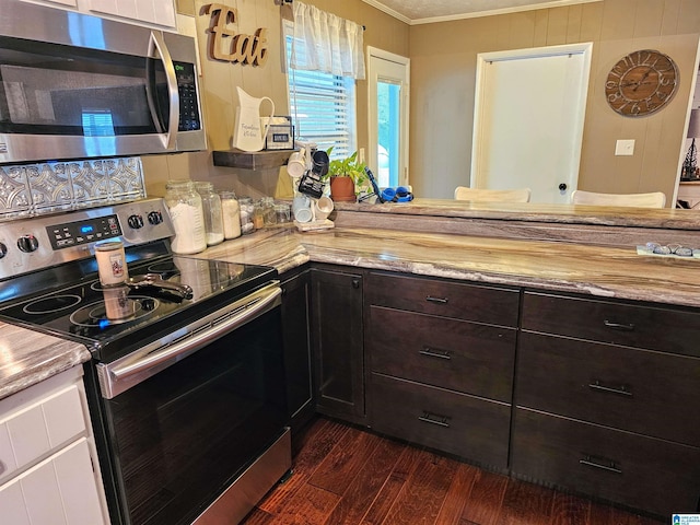 kitchen with dark wood-style flooring, dark brown cabinetry, appliances with stainless steel finishes, white cabinetry, and ornamental molding