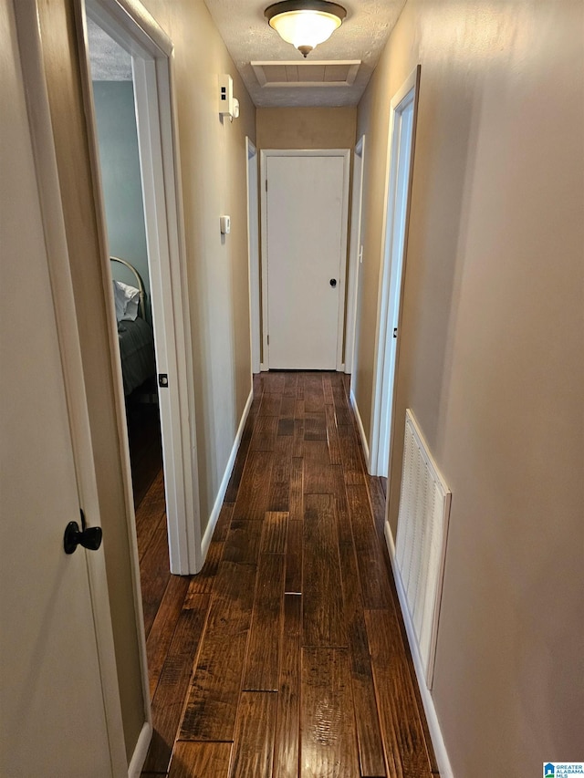hallway featuring baseboards, dark wood-type flooring, and visible vents