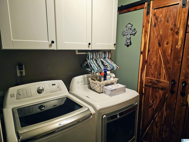 clothes washing area featuring a barn door, cabinet space, and independent washer and dryer