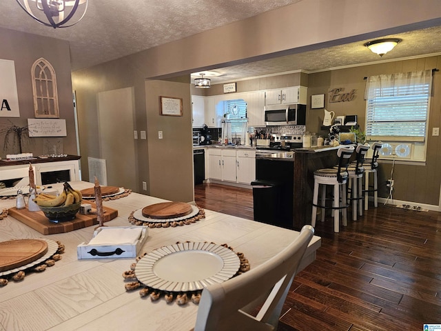 dining area with visible vents, dark wood-type flooring, and a textured ceiling
