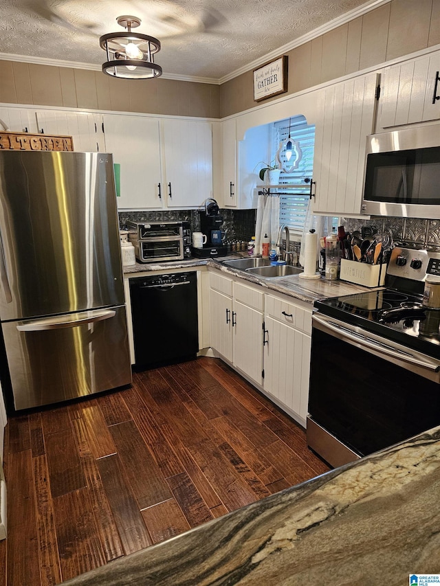 kitchen featuring a sink, crown molding, decorative backsplash, a textured ceiling, and appliances with stainless steel finishes