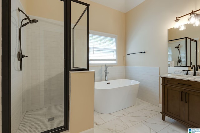 full bath with marble finish floor, a wainscoted wall, vanity, a soaking tub, and a stall shower