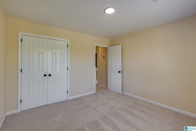 unfurnished bedroom with baseboards, a closet, and light colored carpet