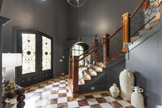 foyer entrance with stairs, arched walkways, french doors, baseboards, and a high ceiling