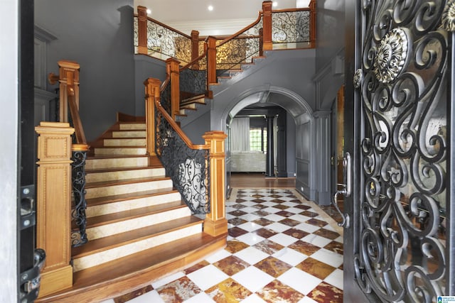 foyer entrance featuring arched walkways, stairway, and a towering ceiling