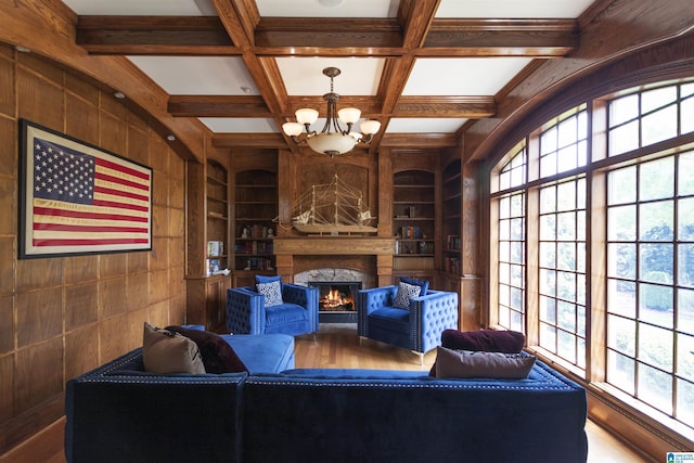 living area with a notable chandelier, wood walls, built in shelves, and a healthy amount of sunlight