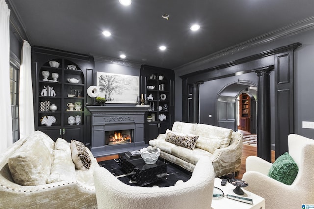 interior space featuring a glass covered fireplace, arched walkways, ornate columns, and crown molding