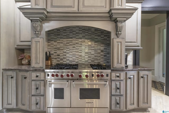 kitchen with backsplash, dark stone counters, and double oven range
