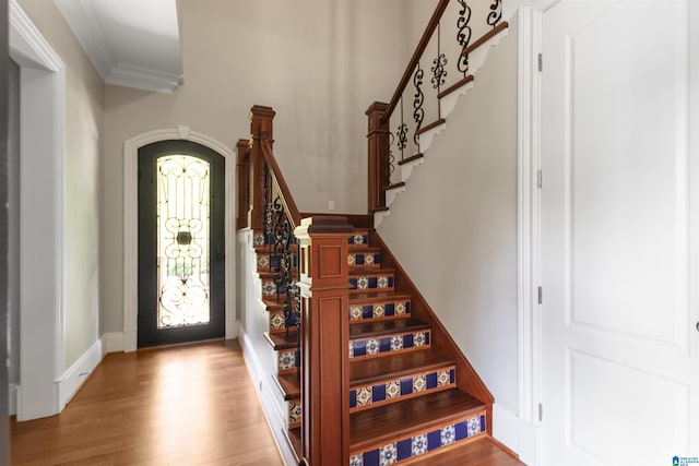 entryway featuring light wood-type flooring, ornamental molding, and stairway