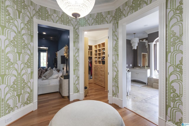 interior space featuring baseboards, ornamental molding, wood finished floors, and wallpapered walls