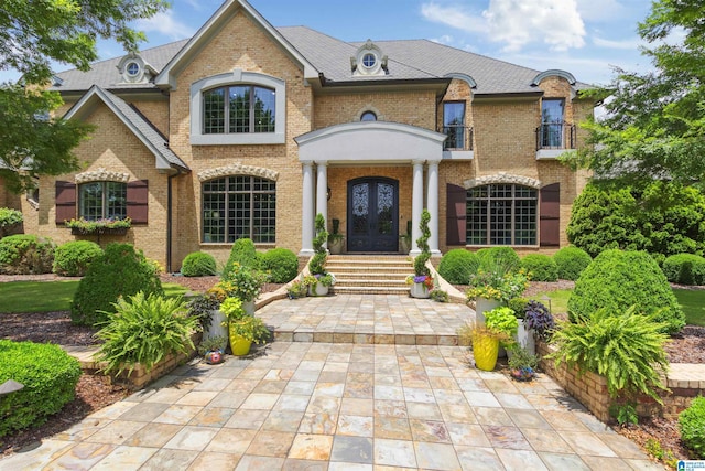 view of front facade with french doors, brick siding, and a balcony