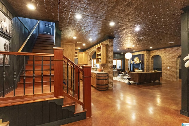 interior space with arched walkways, an ornate ceiling, decorative columns, brick wall, and a lit fireplace