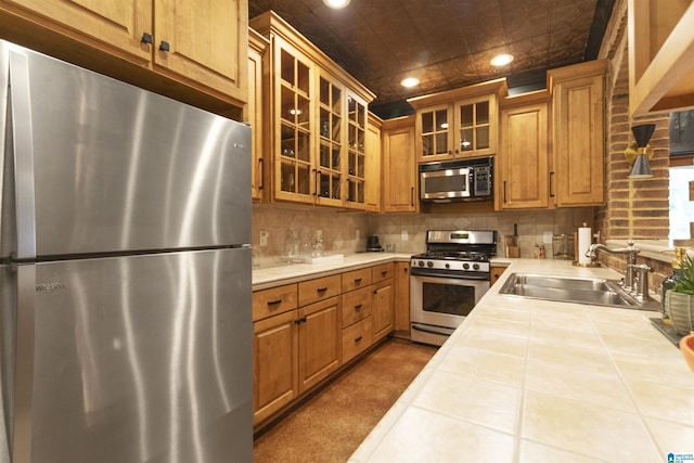 kitchen featuring a sink, tile countertops, decorative backsplash, appliances with stainless steel finishes, and recessed lighting