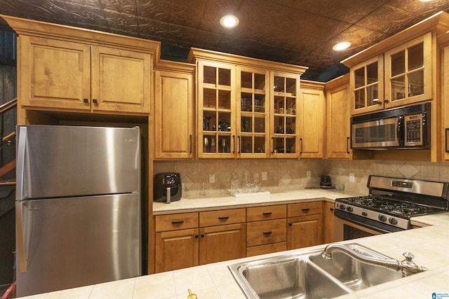 kitchen featuring decorative backsplash, stainless steel appliances, a sink, and an ornate ceiling