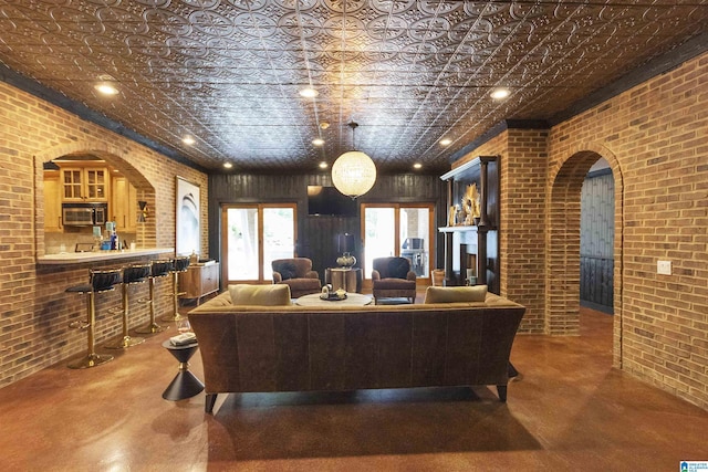 living area featuring brick wall, arched walkways, and an ornate ceiling