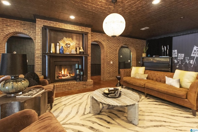 living area with brick wall, a fireplace, arched walkways, and recessed lighting