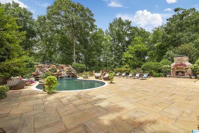 pool with a patio area and an outdoor stone fireplace
