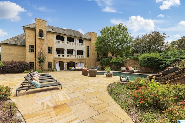 rear view of property with a chimney, a patio, and a balcony