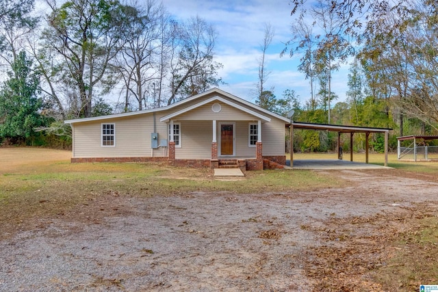 bungalow-style house with dirt driveway, a porch, and an attached carport