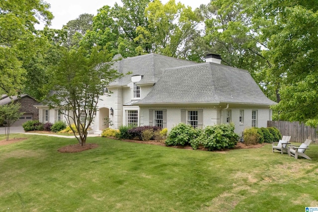 view of front of house featuring a chimney, fence, a front yard, and roof with shingles