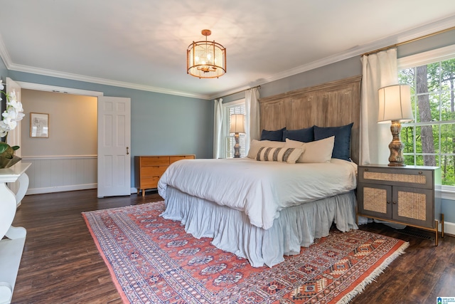 bedroom featuring wood finished floors, crown molding, a notable chandelier, and wainscoting
