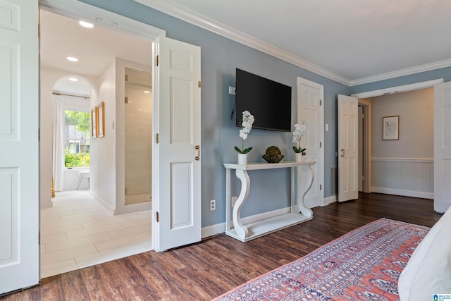 bedroom featuring ornamental molding, arched walkways, wood finished floors, and baseboards