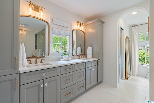 bathroom featuring tile patterned flooring, double vanity, a sink, and baseboards