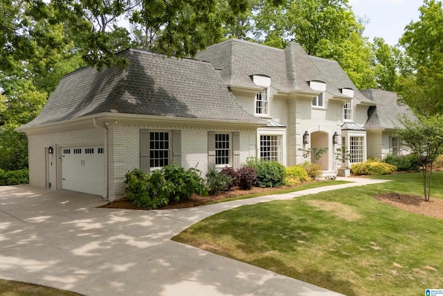 french provincial home featuring a front lawn, a shingled roof, an attached garage, and brick siding