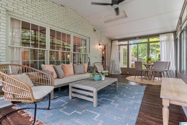 sunroom / solarium with lofted ceiling, attic access, wood finished floors, and brick wall