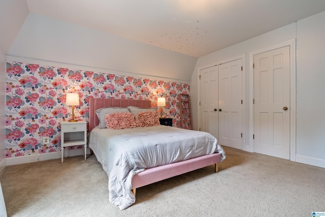 bedroom featuring baseboards, wallpapered walls, lofted ceiling, and carpet flooring