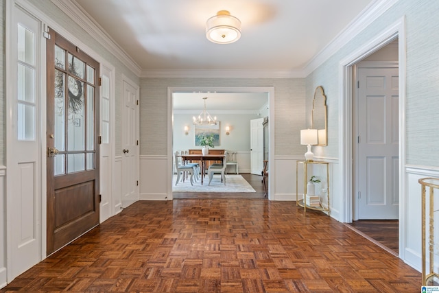 entrance foyer featuring ornamental molding, a wainscoted wall, a notable chandelier, and wallpapered walls